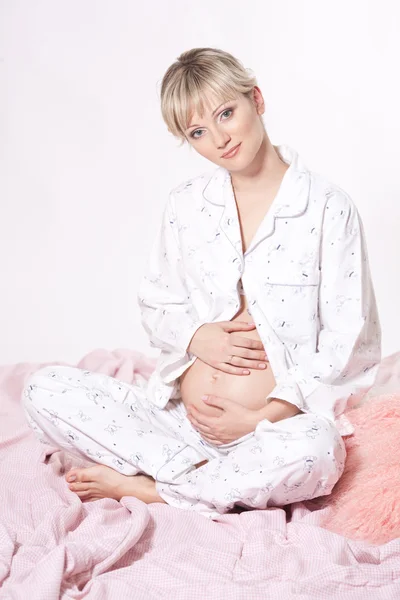 Mulher grávida bonita na cama segurando sua barriga — Fotografia de Stock