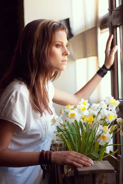 Красива молода жінка дивиться через вікно — стокове фото