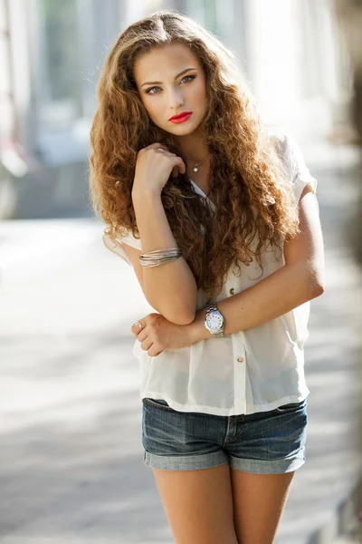 Beautiful young woman with gorgeous curly fair outdoors — Stock Photo, Image