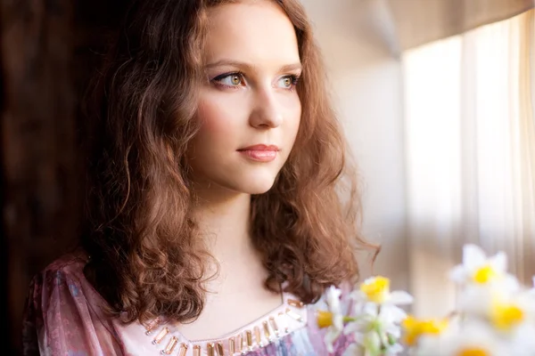 Piękna młoda kobieta, patrząc przez okno — Zdjęcie stockowe