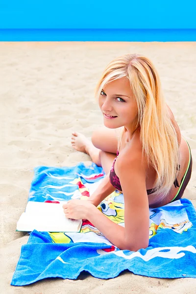 Een vrouw in een zwembroek op een strand lezen van een boek — Stockfoto
