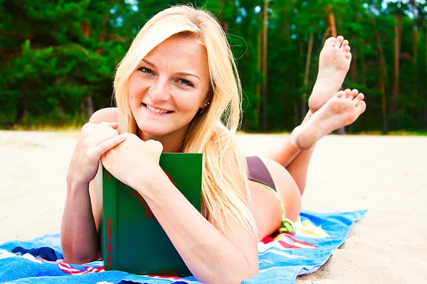 Una mujer en traje de baño en una playa leyendo un libro — Foto de Stock
