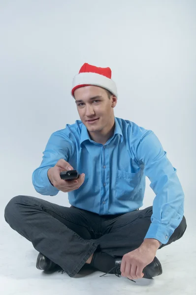 A man with a television remote control watching Christmas TV — Stock Photo, Image