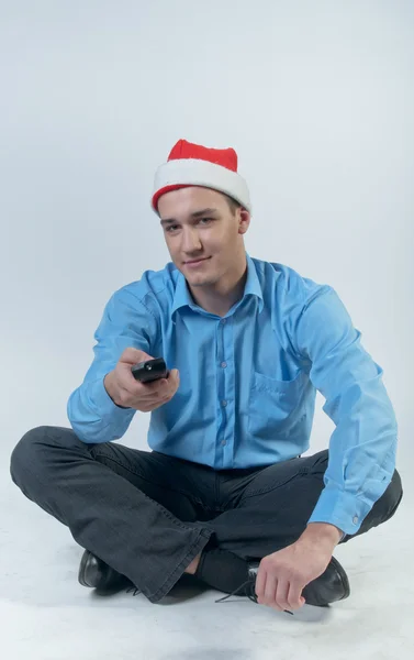 En man med en TV-fjärrkontroll tittar på jul tv — Stockfoto