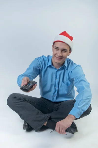 Um homem com controle remoto de televisão assistindo TV de Natal — Fotografia de Stock