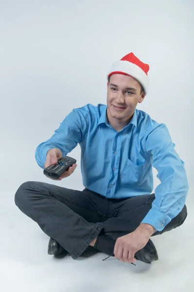 A man with a television remote control watching Christmas TV — Stock Photo, Image