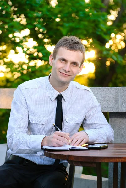 Un hombre de negocios sonriente trabaja desde su oficina en un café al aire libre —  Fotos de Stock