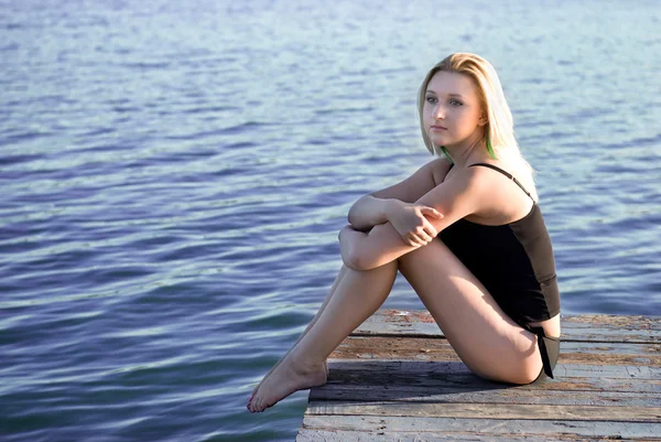Schöne Frau sitzt auf einem Pier — Stockfoto
