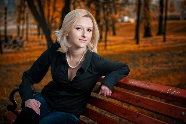 Красивая элегантная женщина, сидящая в парке осенью — стоковое фото