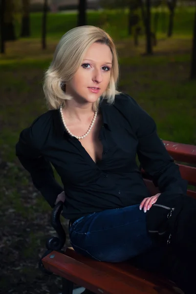 Beautiful elegant woman sitting in a park in autumn Stock Photo