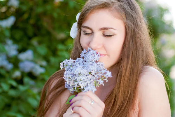 Jovem bela mulher cheirando flor lilás — Fotografia de Stock