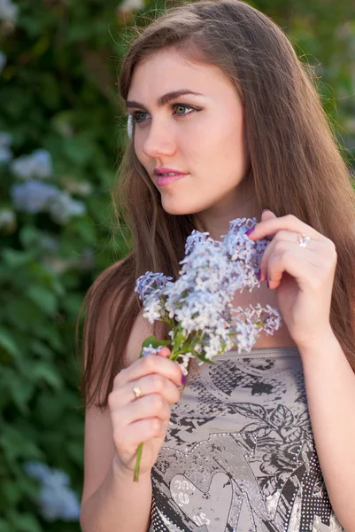 Jovem bela mulher cheirando flor lilás — Fotografia de Stock