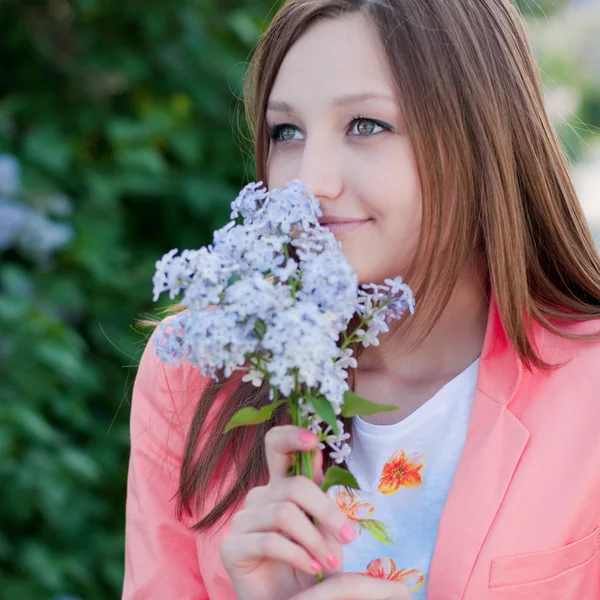 Молодая красивая женщина нюхает лиловый цветок — стоковое фото