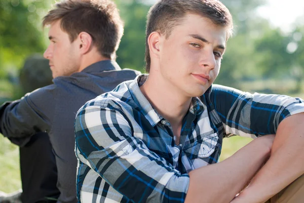 Two young men sitting back to back — Stock Photo, Image
