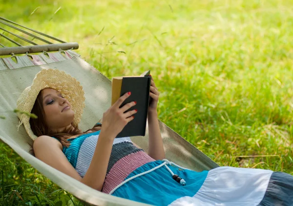 Giovane bella donna che riposa in giardino con libro — Foto Stock
