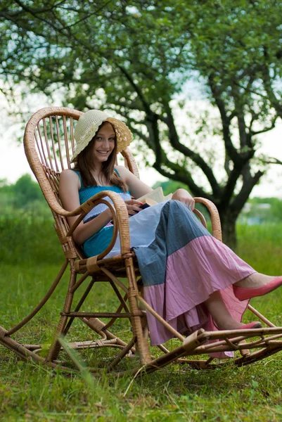 Όμορφη κοπέλα ανάπαυσης στον κήπο με το βιβλίο — Φωτογραφία Αρχείου