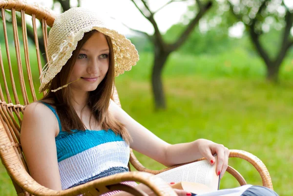 Молодая красивая женщина отдыхает в саду с книгой — стоковое фото