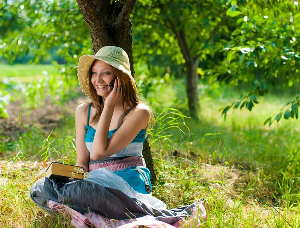 Счастливая девочка-подросток с книгой и мобильным телефоном на улице — стоковое фото