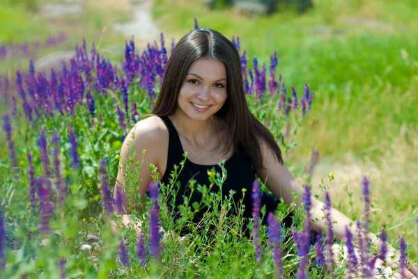 Junge glückliche Frau, die inmitten von Feldblumen ruht — Stockfoto
