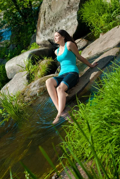 Genç, mutlu, güzel bir kadın nehir kenarında oturuyor. — Stok fotoğraf