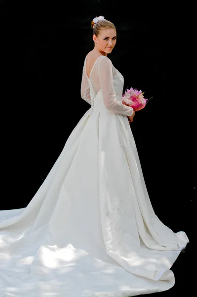 Junge schöne Braut schaut über die Schulter auf schwarzem Hintergrund — Stockfoto