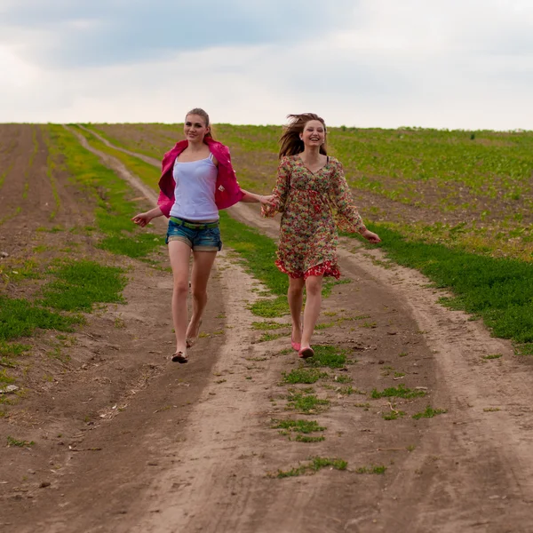 Zwei glückliche Mädchen laufen auf Landstraße — Stockfoto