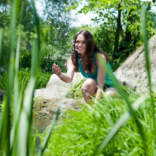 Young happy beautiful woman sitting by the river — Stock Photo, Image