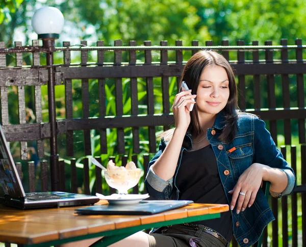 Νεαρή ευτυχισμένη γυναίκα που κάθεται στην βεράντα café με laptop — Φωτογραφία Αρχείου