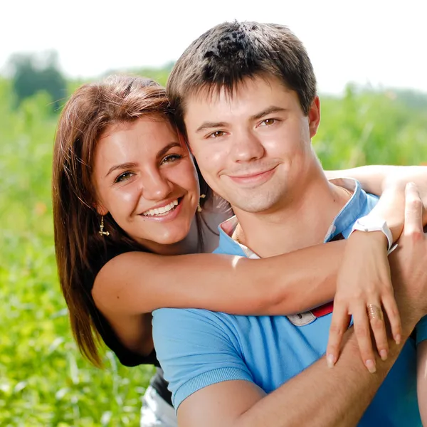 Mladý šťastný pár sedící na zelené trávě — Stock fotografie