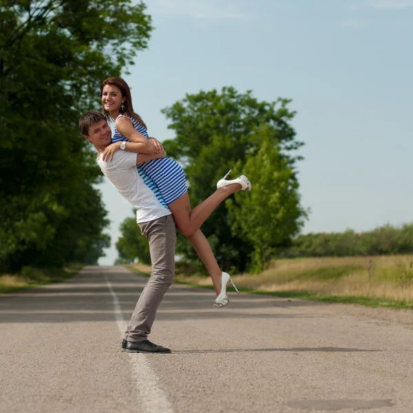 Młoda szczęśliwa para spaceru wzdłuż drogi — Zdjęcie stockowe