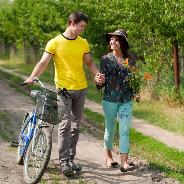 Young happy couple walking with bicycle — Stock Photo, Image