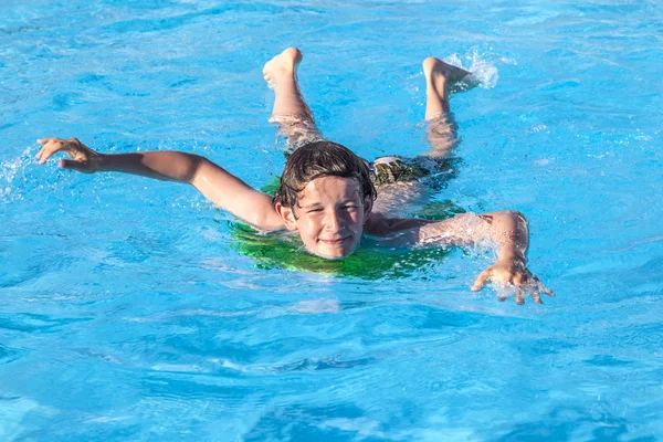 Rapaz relaxante numa prancha de surf na piscina — Fotografia de Stock