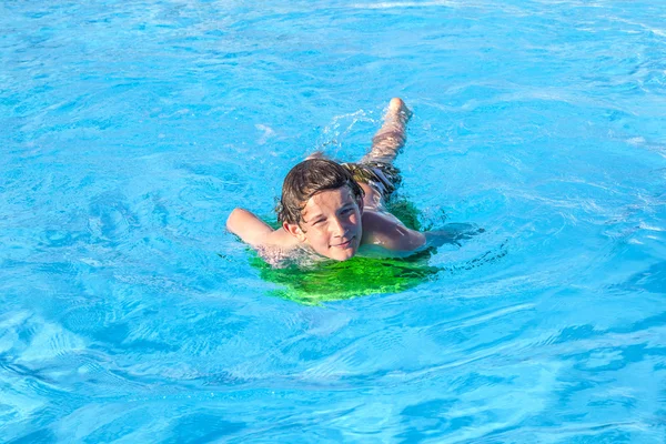 Niño relajándose en una tabla de surf en la piscina — Foto de Stock