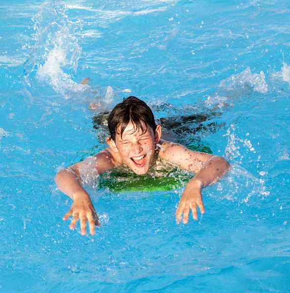 Jongen heeft plezier op de surfplank in het zwembad — Stockfoto
