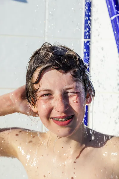 Menino se diverte usando o chuveiro da piscina — Fotografia de Stock