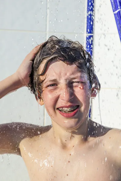 Menino se diverte usando o chuveiro da piscina — Fotografia de Stock