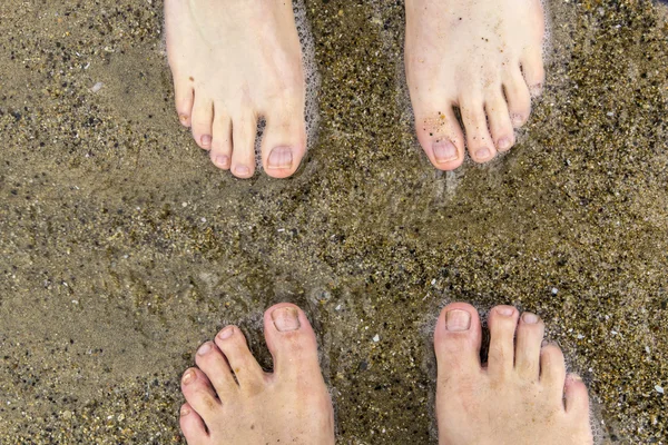 Fötter av far och son på stranden — Stockfoto
