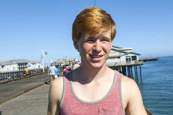 Lachende aantrekkelijke jongen houdingen tegenover de pier — Stockfoto