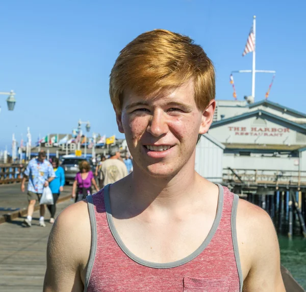 Lachende aantrekkelijke jongen houdingen tegenover de pier — Stockfoto