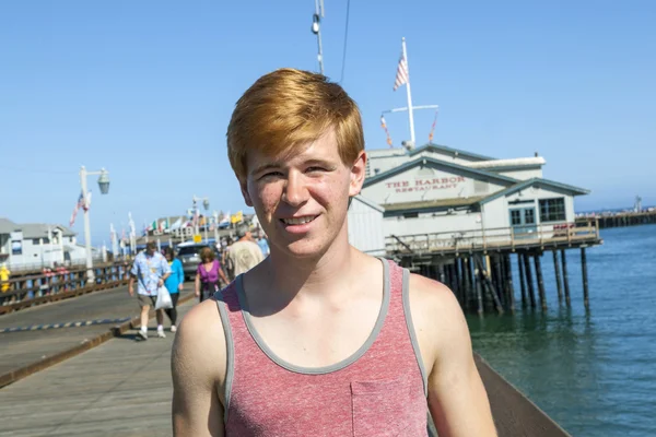 Sorridente attraente ragazzo posa di fronte al molo — Foto Stock