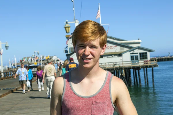 Sorridente attraente ragazzo posa di fronte al molo — Foto Stock