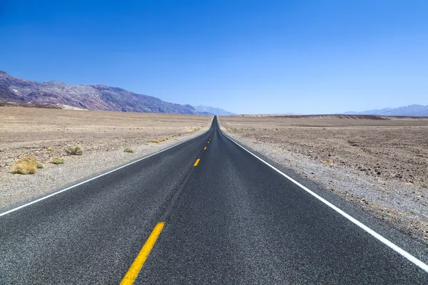 Death Valley road straight across the desert to the mountains in — Stock Photo, Image