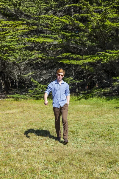 Adolescente com óculos de sol caminha feliz no prado — Fotografia de Stock