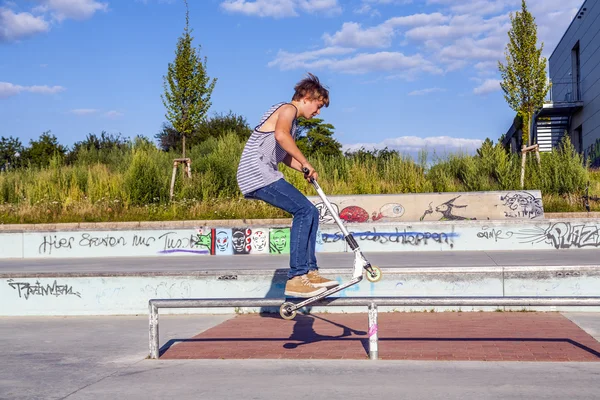 Boy has fun jumping with his scooter at the skate park — Stock Photo, Image