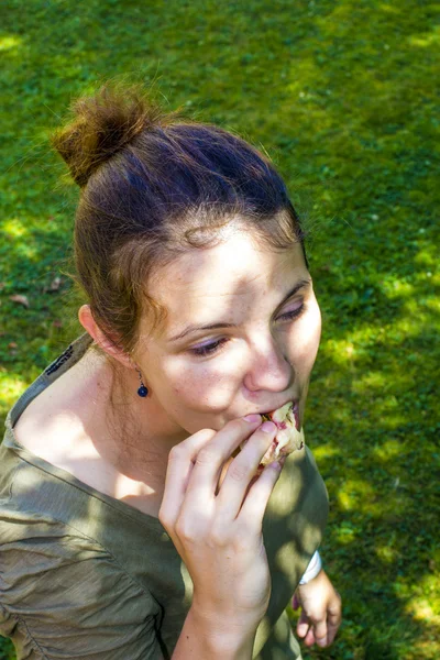 Stock image Young woman enjoys eating a peach in the garden