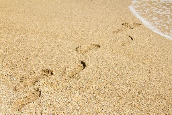 Fußspuren, die vom Betrachter ins Meer führen — Stockfoto