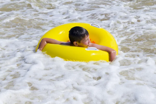 El niño está bañado en un mar de círculo de goma amarilla —  Fotos de Stock