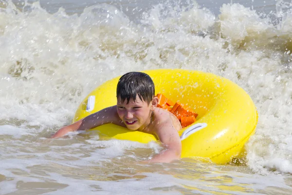 El niño está bañado en un mar de círculo de goma amarilla — Foto de Stock