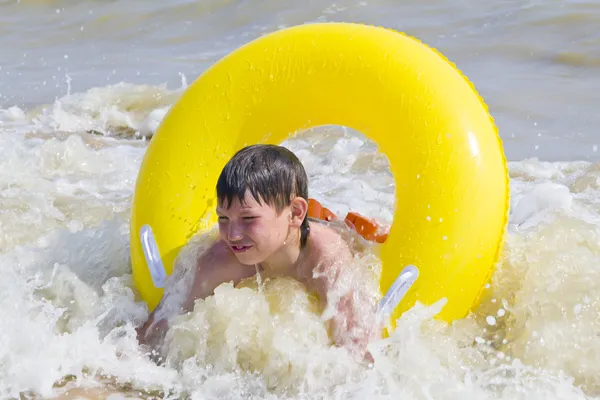 Το παιδί είναι λουσμένο σε μια θάλασσα από κίτρινο καουτσούκ κύκλο — Φωτογραφία Αρχείου
