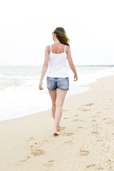 stock image Woman in denim shorts walking on beach